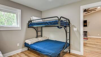 Una cama litera con colchón azul en una habitación con suelo de madera y ventana.
