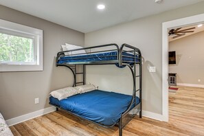 A bunk bed with a blue mattress in a room with wooden flooring and a window.