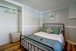 A bedroom with a single bed, a wall-mounted shelf, and a small trash bin. - Steps to Beach! Topsail Island Retreat (Surf City)