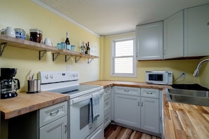 A compact kitchen with white cabinets, a built-in oven, a microwave, and a coffee maker on the counter. - Steps to Beach! Topsail Island Retreat (Surf City)