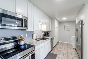 A modern kitchen with stainless steel appliances, white cabinetry, and a tiled backsplash. - Game Room & Hot Tub! Bayfront Family Gem (Fort Walton Beach)