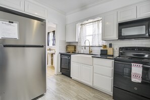 A modern kitchen with white cabinetry, stainless steel appliances, and a window with patterned curtains. - San Angelo Lake Escape: Dock & Fire Pit (San Angelo)