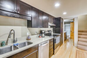 A modern kitchen with stainless steel appliances, dark wooden cabinets, and a white countertop. - Walk to Ski Slopes! Sun Valley Condo w/ Balcony (Ketchum)