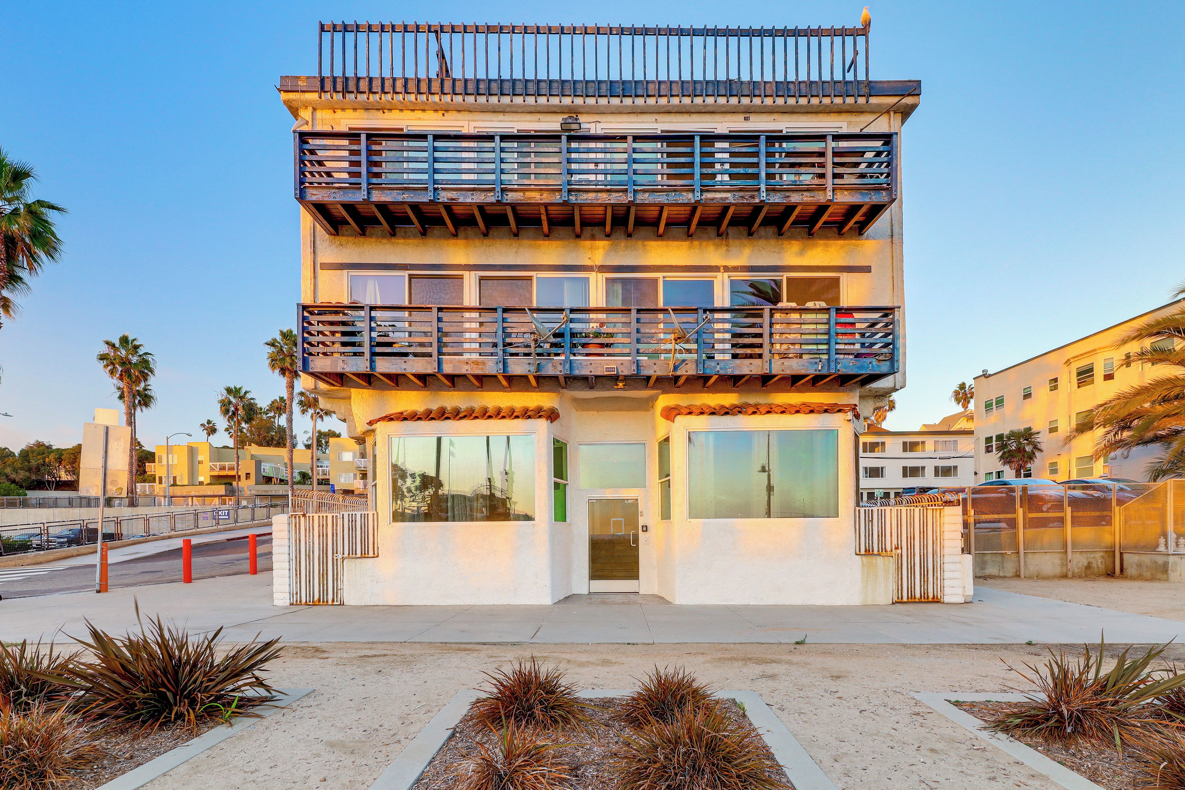 A two-story building with a balcony, large windows, and a gated entrance.