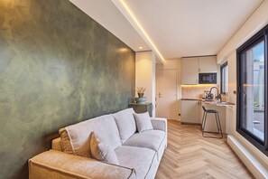 A modern living room with a sofa, a dining area with a bar, and a kitchen with a microwave. - New Studio Eiffel Tower-Trocader with terrace (Paris)