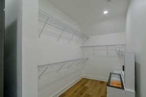 A room with a wooden floor, white walls, and metal wire shelving units for storage. - Bright & Modern Studio, 15 Mi to Des Moines! (Waukee)