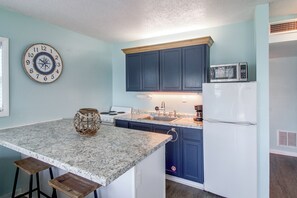 A kitchen with a central island, a microwave, and a clock on the wall. - Water Views! Studio w/ Hot Tub & Boat Dock Access (Fort Walton Beach)