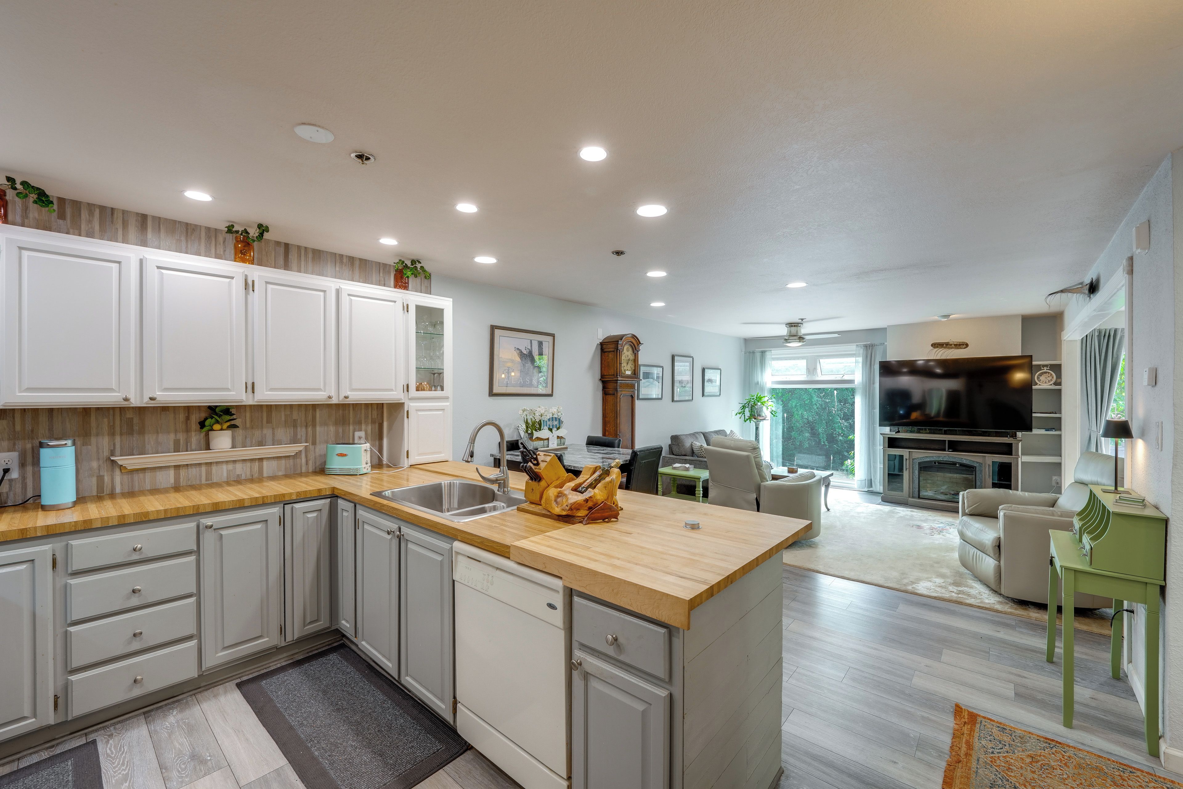 A modern kitchen with a wooden countertop, white cabinets, and a built-in sink.