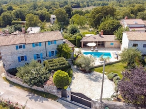 A stone villa with a swimming pool, surrounded by lush greenery and a stone wall. - Villa in Porec With Swimming Pool (Porec)