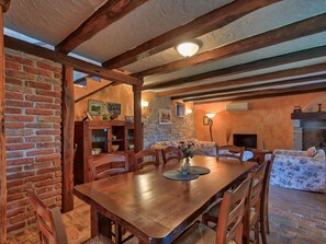 A rustic dining room with a wooden table and chairs, a brick wall, and a stone fireplace. - Villa in Porec With Swimming Pool (Porec)