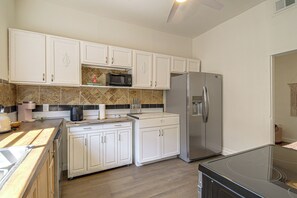 A kitchen with white cabinets, a stainless steel refrigerator, a microwave, and a coffee maker. - 1 Mi to Dtwn! Pensacola Extended Stay (Pensacola)