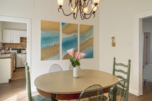 A dining area with a round table, chairs, a vase with flowers, and wall art. - 1 Mi to Dtwn! Pensacola Extended Stay (Pensacola)