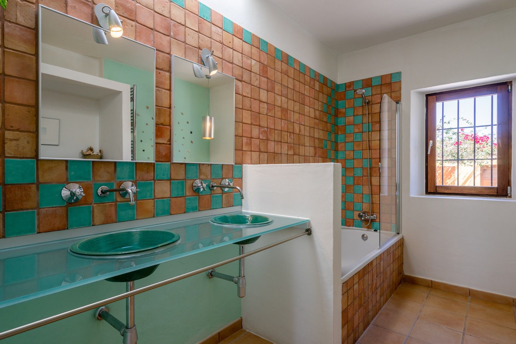Un baño con dos lavamanos, un espejo, ducha y ventana con vistas.