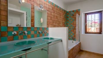 Un baño con dos lavamanos, un espejo, ducha y ventana con vistas.