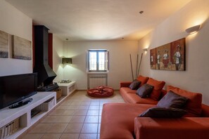 Una sala de estar con televisión de pantalla plana, chimenea, ventana y sofá.