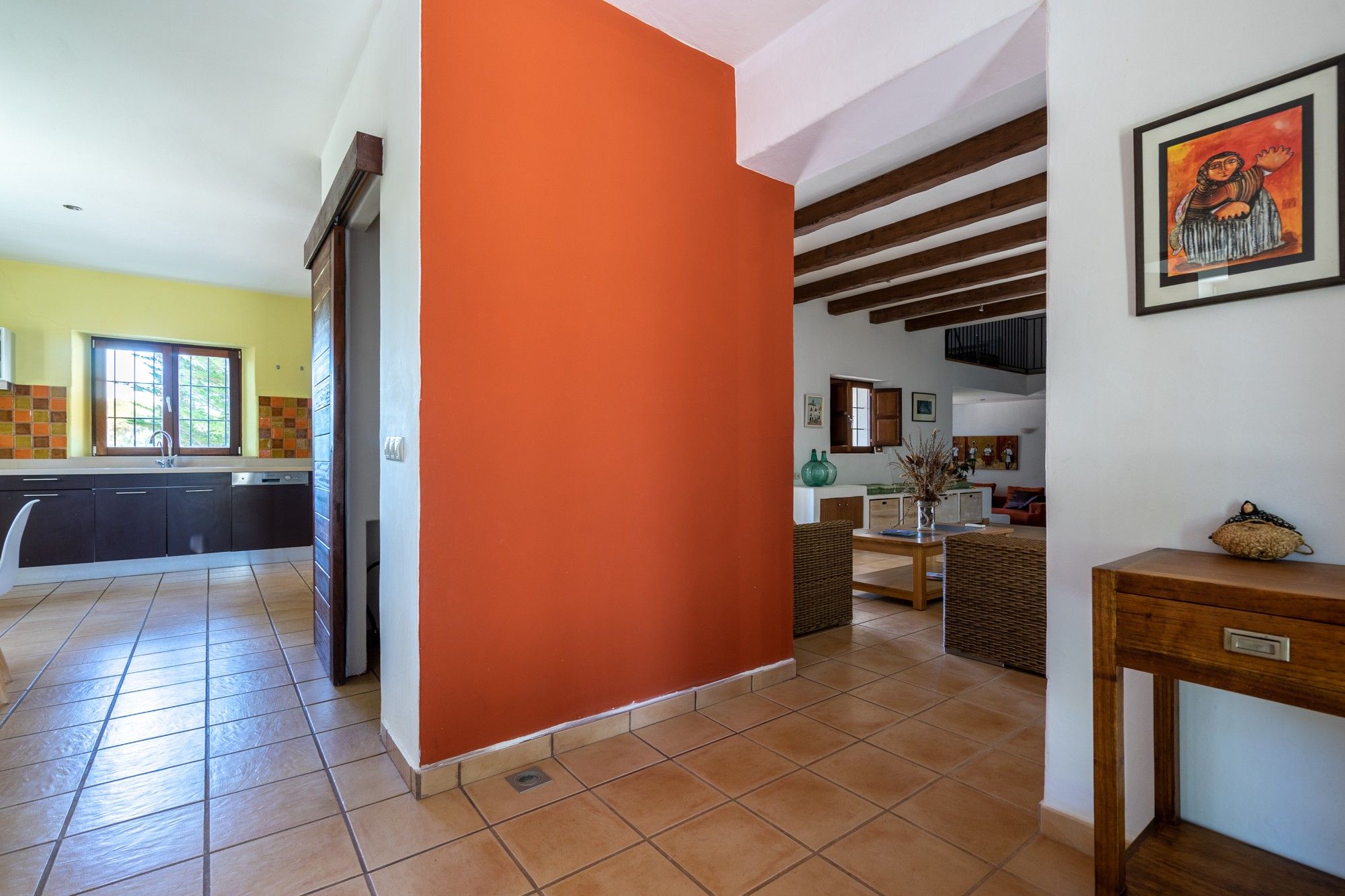 Un'ampia cucina con elettrodomestici moderni, una zona pranzo con tavolo in legno e un soggiorno con divano e opere d'arte.