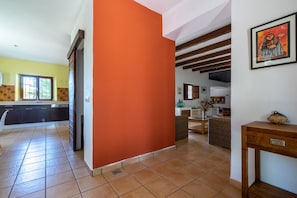 A spacious kitchen with modern appliances, a dining area with a wooden table, and a living space with a sofa and artwork.
