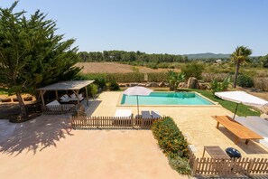 Un giardino con piscina, area relax all'aperto e terrazza in legno.