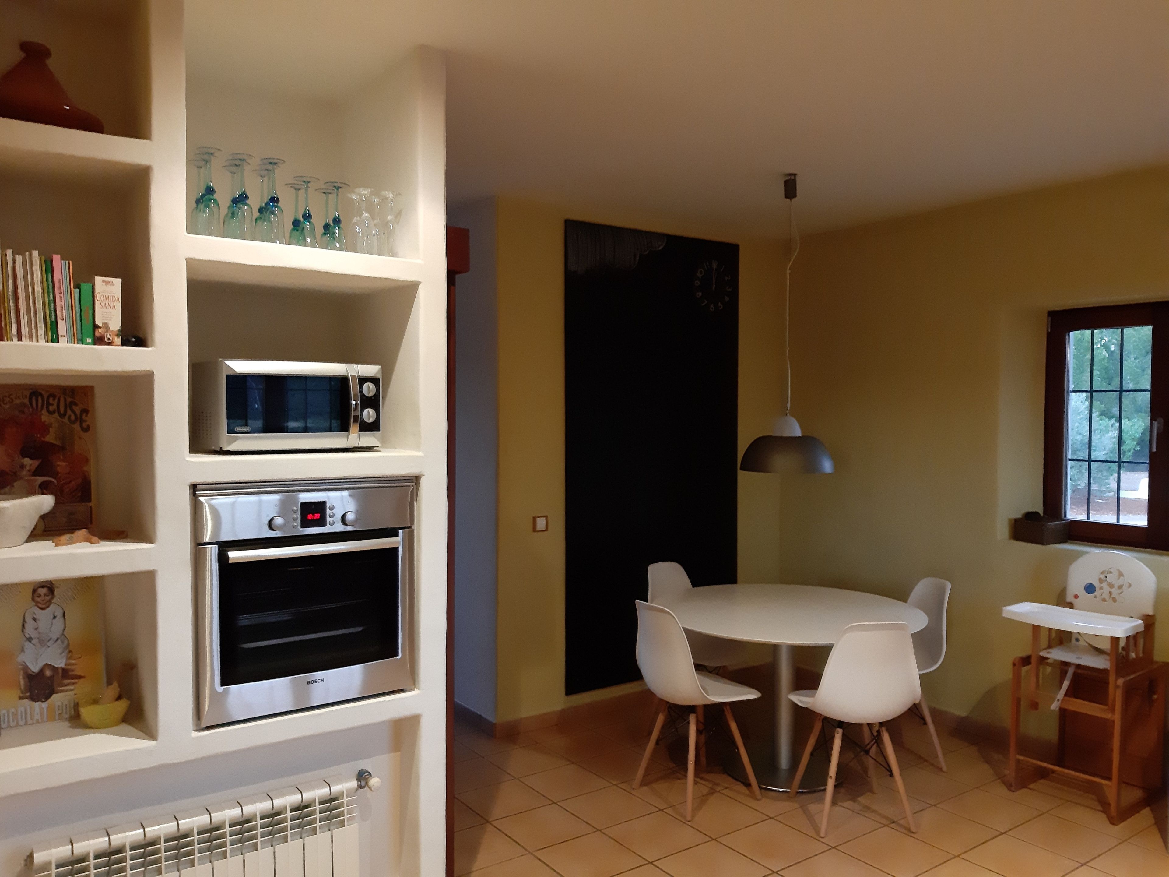 Una cucina con forno a microonde, forno e tavolo da pranzo con sedie.