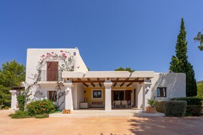 Una casa moderna con un portico coperto, una porta in legno e un balcone fiorito.
