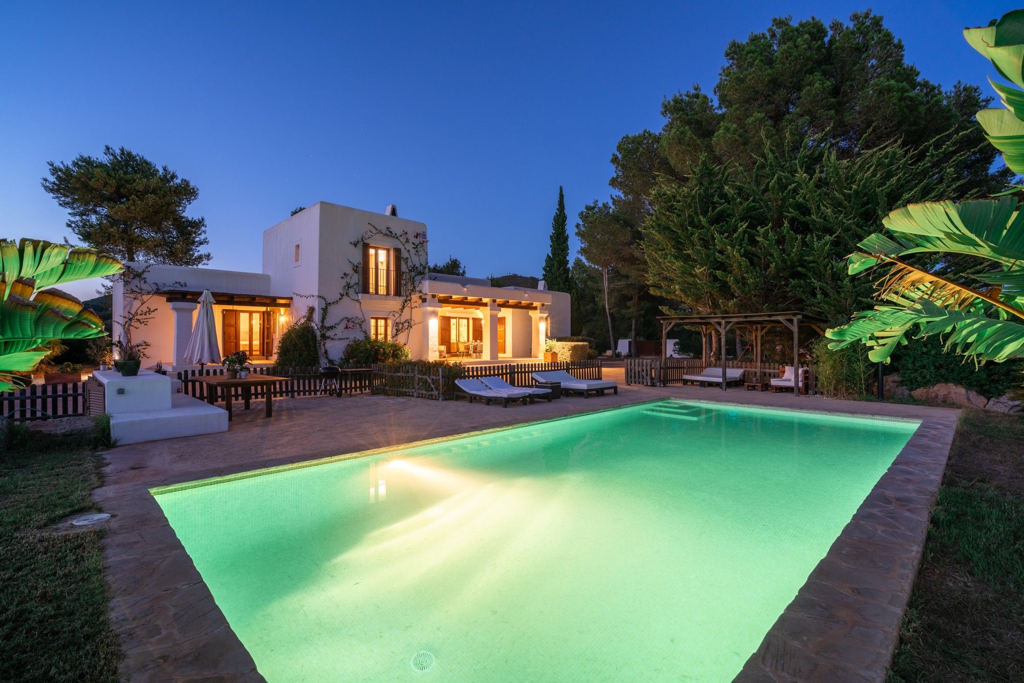 A modern house with a swimming pool, outdoor seating, and a well-lit patio area.