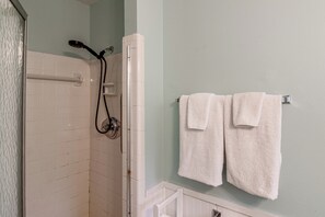 Ein Badezimmer mit Dusche, einem Handtuchhalter mit zwei Handtüchern und einer weißen Badewanne.
