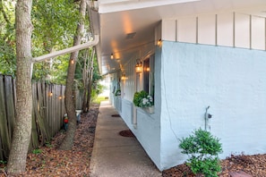 A covered porch with string lights, a wooden fence, and a pathway leading to a house. - Hot Tub & Dock Access! Bayfront Studio (Fort Walton Beach)