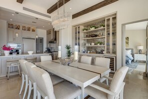 A modern kitchen with a dining area, featuring a chandelier, built-in cabinets, and a large island with seating. - Pool, Hot Tub & Outdoor Kitchen! Palmilla Escape (San José del Cabo)