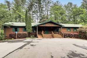 A lodge with a wooden exterior, a porch, and a staircase leading to the entrance. - Ellijay Mtn Cabin w/ Hot Tub & Community Perks! (Ellijay)
