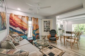 A living room with a sofa, glass coffee table, and a dining area with chairs and a table. - Steps to Dtwn & Riverwalk! Retreat w/ Fenced Yard (Bradenton)