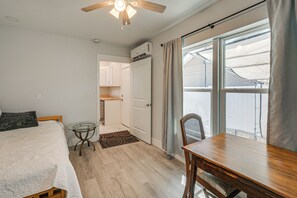 A bedroom with a bed, a small table, a chair, a ceiling fan, and a view of the outdoors through a window. - Steps to Dtwn & Riverwalk! Retreat w/ Fenced Yard (Bradenton)