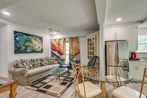 A modern living room with a sofa, a glass dining table, and a ceiling fan. - Steps to Dtwn & Riverwalk! Retreat w/ Fenced Yard (Bradenton)