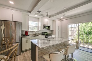 A modern kitchen with a large island, stainless steel appliances, and a view of greenery outside. - Steps to Dtwn & Riverwalk! Retreat w/ Fenced Yard (Bradenton)