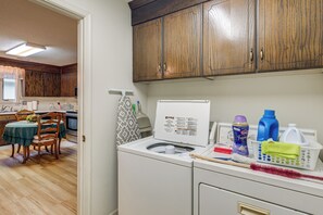 A kitchen with wooden cabinets, a dining table with chairs, and a washing machine with detergent bottles. - Private Yard & Patio! Hopewell Extended Stay (Hopewell)