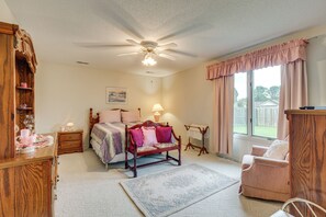 A bedroom with a bed, bedside tables, a nightstand, a chair, a window with curtains, and a ceiling fan. - Private Yard & Patio! Hopewell Extended Stay (Hopewell)