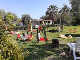 Un parque infantil con columpios, toboganes y una pequeña mesa con sillas.