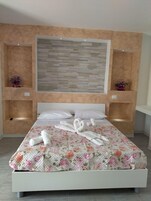 Una cama con una colcha estampada con motivos florales, dos almohadas blancas y una pared con un diseño texturizado.