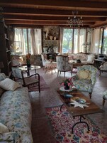 Un salon chaleureux, doté de meubles à motifs floraux, d’un lustre et offrant une vue sur l’extérieur.