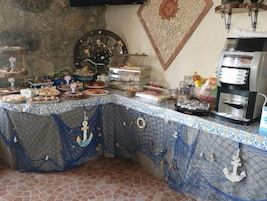 Montaje de bufé con diversas opciones de comida, una máquina de café y una pared decorativa con motivos de sol.