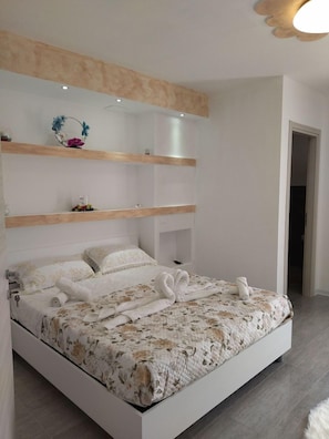 Un dormitorio moderno con una cama grande, estanterías empotradas y un elemento decorativo en la pared.