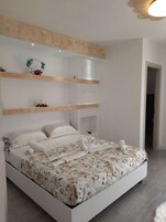 Quarto moderno com uma cama grande, estantes embutidas e um objeto decorativo na parede.