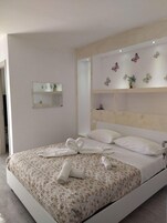 Une chambre moderne avec un grand lit, un miroir de chevet et des décorations murales représentant des papillons.