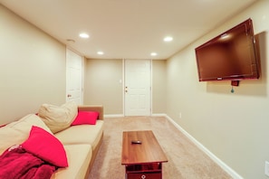 A room with a beige sofa, red pillows, a wooden coffee table, and a mounted flat-screen TV. - Yard & Patio Family Home Near Pittsburgh (West Mifflin)