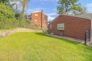 A residential property with a well-maintained lawn, a brick house, and a neighboring building. - Yard & Patio Family Home Near Pittsburgh (West Mifflin)