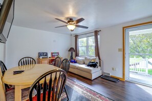 A dining area with a table and chairs, a ceiling fan, a window with curtains, and a view of greenery outside. - Yard & Patio Family Home Near Pittsburgh (West Mifflin)