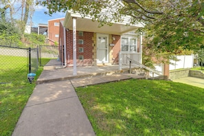 A residential house with a brick facade, a front porch, and a fenced yard. - Yard & Patio Family Home Near Pittsburgh (West Mifflin)