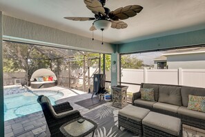 Ein überdachter Außenbereich mit Pool, Sitzgelegenheiten und Deckenventilator.