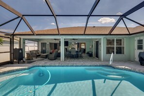 A covered outdoor swimming pool with a patio area, including seating and a table. - Saltwater Pool & Firepits: Cape Coral Home (Cape Coral)