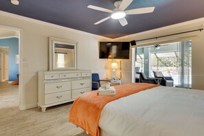 Ein Schlafzimmer mit Bett, Kommode, Spiegel, Deckenventilator und Blick ins Freie.