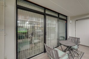 Ein Balkon mit Tisch und Stühlen, eine Schiebetür und Blick auf die Straße.